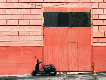 Motor scooter parked against brick wall