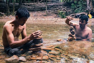 Men sitting on rock by water