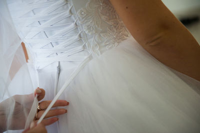 Cropped hands of bridesmaid dressing bride during wedding ceremony