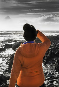 Rear view of man standing at beach against sky