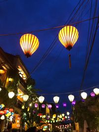 Low angle view of illuminated lanterns hanging against sky at night