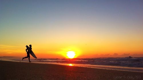 Silhouette of people on beach at sunset