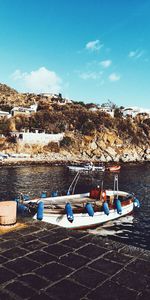 Boats moored on beach against blue sky