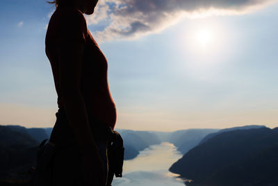 Midsection of pregnant woman standing against sky