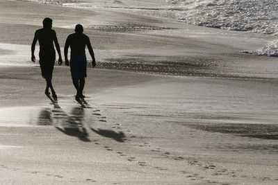 Silhouette of two men walking on beach