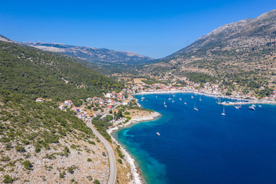 High angle view of sea and mountains against blue sky