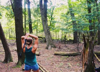Rear view of woman photographing in forest