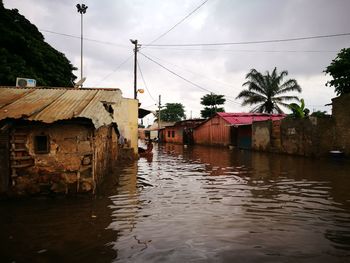 Houses amidst water during flood against cloudy sky