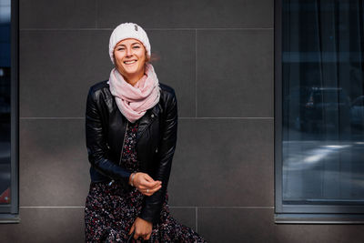 Beautiful modern urban young woman wearing pink knitting hat, black coat