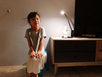 Smiling cute girl sitting by table at home