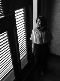 Young woman standing by window at home