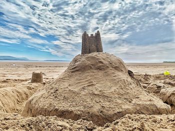 Rock formation on beach against sky