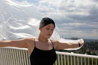 Young woman looking away while standing against railing