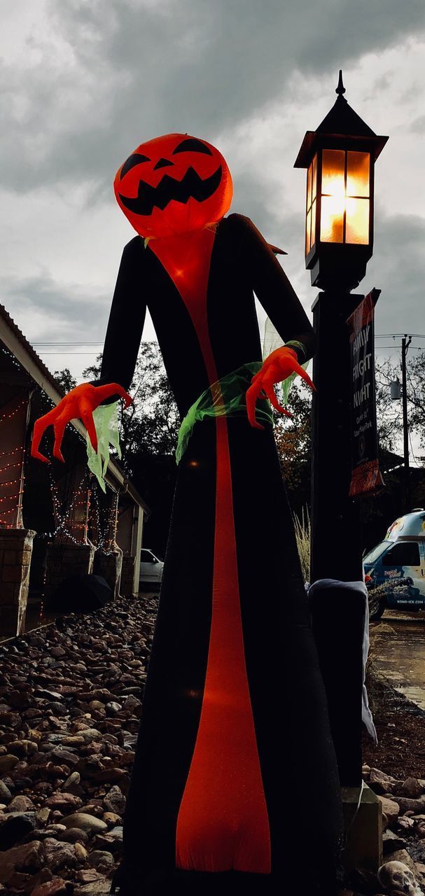 WOMAN WITH RED UMBRELLA STANDING BY BUILDING AGAINST SKY