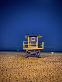 Lifeguard hut on beach against blue sky