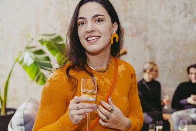 Portrait of smiling female entrepreneur holding drink glass during event at convention center