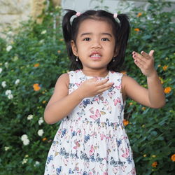 A cute asian kid girl wearing butterflies pattern dress with pigtail hair showing funny pose