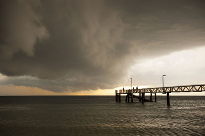 Pier over sea against sky during sunset