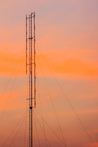 Low angle view of silhouette electricity pylons against sky during sunset