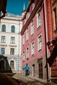 Rear view of man walking on street by building