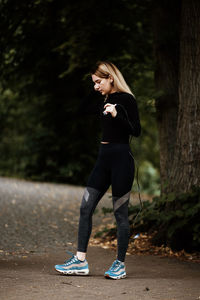 Side view of young woman standing against trees