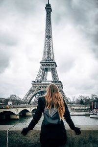 Rear view of woman standing against cloudy sky