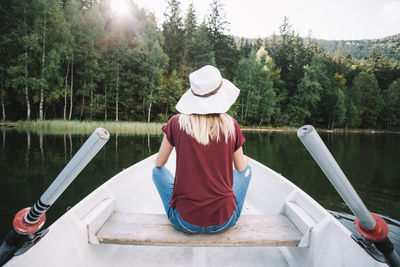 Rear view of woman sitting on boat against lake