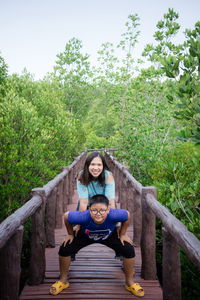 Portrait of mother and son on footbridge against trees