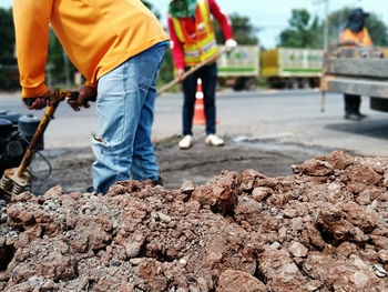 Midsection of workers digging on road