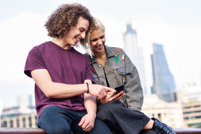 Young couple sitting on railing in city