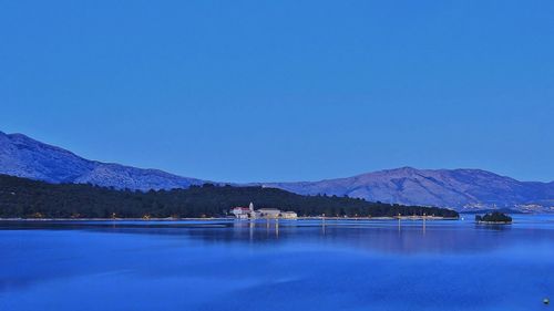 Scenic view of lake and mountains against clear blue sky