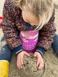 Close-up of cute girl playing on sand at beach