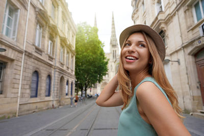 Stylish traveler girl turns around when walking in bordeaux street, france