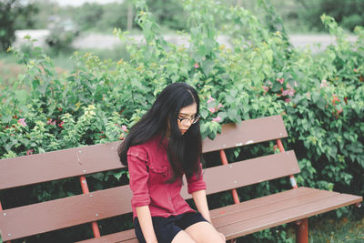 Full length portrait of woman smiling while sitting on bench