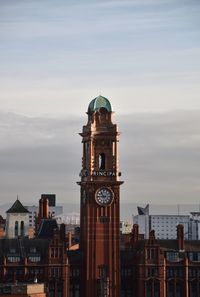 Clock tower amidst buildings in city against sky