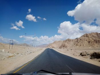 Road leading towards mountains against sky