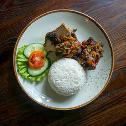 High angle view of grilled ribs rice in plate on wood table
