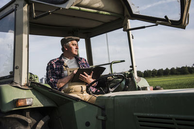 Farmer sitting in tractor using digital tablet