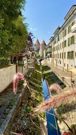 Canal amidst buildings in old city of yverdon-les-bains against sky