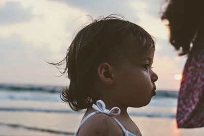 Close-up of baby girl at beach during sunset