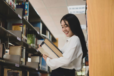 Young woman reading book at library