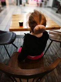 Rear view of woman sitting on table at cafe