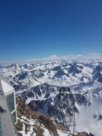 Aerial view of snowcapped mountains against clear blue sky