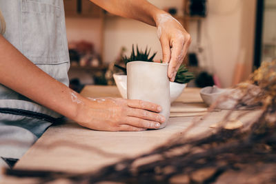 Midsection of woman preparing pottery on table