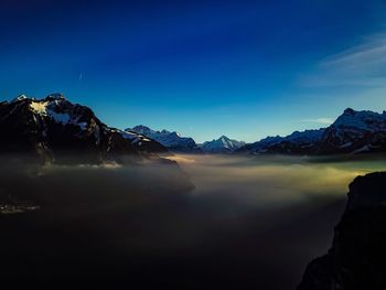 Scenic view of snowcapped mountains against blue sky