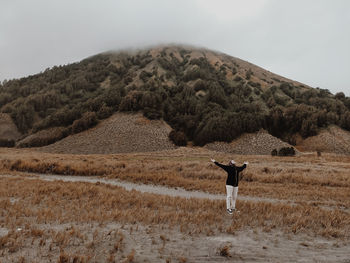 Rear view of woman walking on mountain against sky