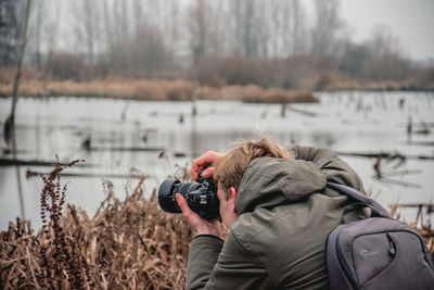 Midsection of man photographing by lake