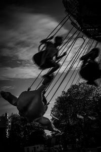 Low angle view of people at amusement park against sky