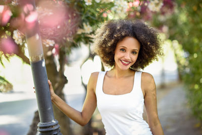 Portrait of smiling young woman standing by garden light