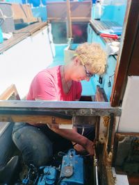 Woman repairing motor in boat